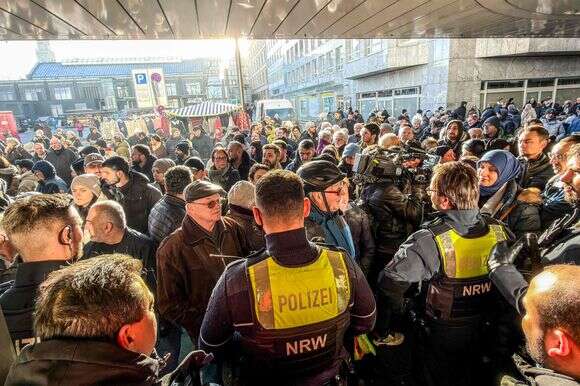 Christoph Reichwein / dpa / AFP | שוטרים ולקוחות מודאגים עומדים מול סניף של בנק Sparkasse בגלזנקירכן, מערב גרמניה, ב-30 בדצמבר 2025, לאחר שהבנק נשדד