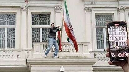 אדם מוריד את דגל איראן במהלך הפגנות נגד המשטר האיראני מול שגרירות איראן בלונדון | AFP