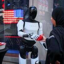 רובוט של טסלה אופטימוס מחלק ממתקים מול בורסת נאסד"ק בניו יורק | מייקל נגל/בלומברג