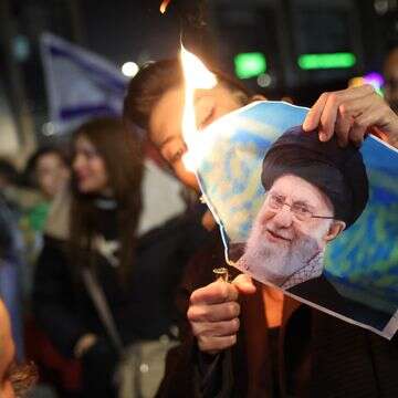 חבר בקהילה הישראלית-איראנית שורף תמונה של המנהיג העליון של איראן, עלי חמינאי, במהלך הפגנה לתמיכה בעם האיראני בחולון | EPA/ABIR SULTAN