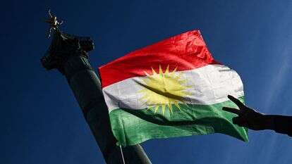 מפגין מניף את סמל השלום באצבעותיו מול דגל כורדיסטן במהלך הפגנת סולידריות עם הכורדים בצפון סוריה | בלנקה קרוז / AFP