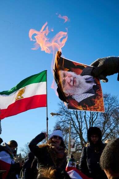 מפגינים שורפים תמונות של המנהיג העליון של איראן, האייתוללה עלי חמינאי | AP