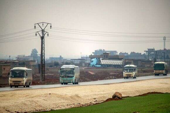 אוטובוסים בשיירה צבאית אמריקאית המובילים עצורים של קבוצת המדינה האסלאמית המועברים לעיראק מסוריה נוסעים לאורך כביש בפאתי קאחטאניה במחוז חסכה בצפון מזרח סוריה ב-7 בפברואר 2026 | AFP