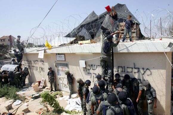 היום, בניגוד להתנתקות, היחסים עם המשטרה והצבא טובים. מתיישבים מתבצרים על אחד הגגות בחומש, 2005 | מנחם כהנא, איי.אף.פי