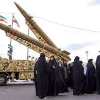 נשים הולכות ליד כלי שיגור טילים בליסטיים בטהרן ב-11 בפברואר 2026, במהלך עצרת לציון 47 שנה למהפכה האסלאמית ב-1979 | AFP