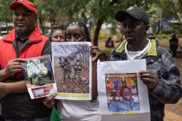 קרובי משפחה של אזרחים קנייתים שגויסו לצבא הרוסי באוקראינה מצטלמים עם תמונות של בני משפחותיהם | AFP