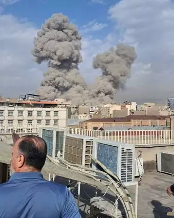 אנשים צופים בעשן עולה מעל קו הרקיע לאחר פיצוץ בטהרן | AP אנשים צופים בעשן עולה מעל קו הרקיע לאחר פיצוץ בטהרן | AP