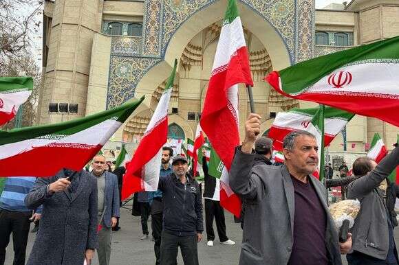 קבוצת גברים מנופפת בדגלי איראן בהפגנה לתמיכה בממשלה ונגד תקיפות אמריקניות וישראליות בטהרן | AP