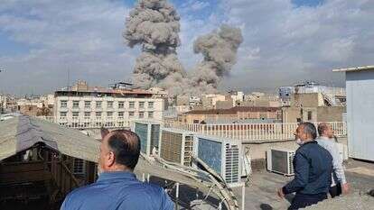 אנשים צופים בעשן עולה מעל קו הרקיע לאחר פיצוץ בטהרן, איראן | AP