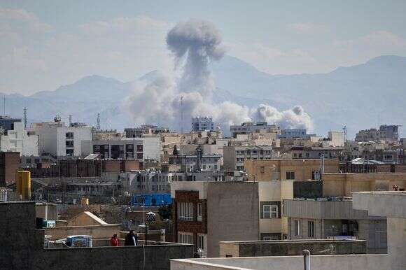 אנשים צופים מהגג בעשן עולה לאחר תקיפה בטהרן, איראן | AP