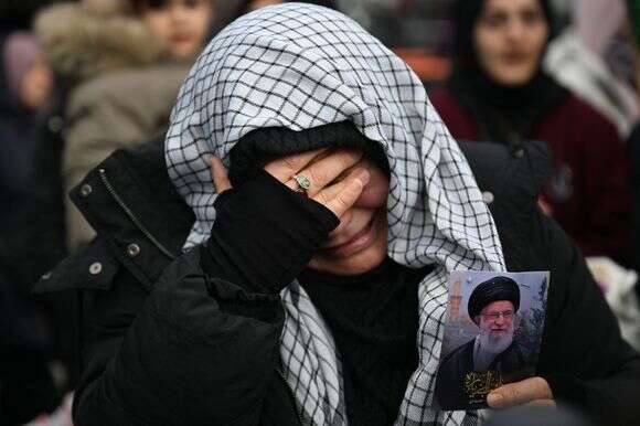 מפגינים אוחזים בתמונה של האייתוללה עלי חמינאי כשהם מתאספים במחאה נגד התקיפות האמריקניות והישראליות על איראן | AFP