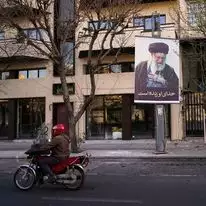 אופנוע חולף על פני תמונה של המנהיג העליון האיראני, האייתוללה עלי חמינאי, לאורך רחוב ריק בטהרן, איראן | AP/Vahid Salemi