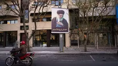 אופנוע חולף על פני תמונה של המנהיג העליון האיראני, האייתוללה עלי חמינאי, לאורך רחוב ריק בטהרן, איראן | AP/Vahid Salemi