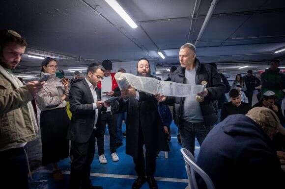 אנשים קוראים את מגילת אסתר בערב פורים בחניון תת קרקעי בתל אביב | מרים אליסטר - פלאש 90