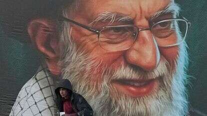 פועל מתקין שלט חוצות על גשר ובו דיוקנו של המנהיג העליון האיראני, האייתוללה עלי חמינאי, שנהרג במהלך המערכה הצבאית המשותפת של ארה"ב וישראל, בטהרן | AP Photo/Vahid Salemi