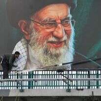 עובדים מציבים שלט חוצות על גשר ובו דיוקנו של המנהיג העליון האיראני, האייתוללה עלי חמינאי, שנהרג במהלך התקפות צבאיות משותפות של ארה"ב וישראל | AP/Vahid Salemi