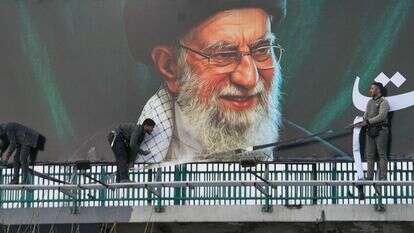 עובדים מציבים שלט חוצות על גשר ובו דיוקנו של המנהיג העליון האיראני, האייתוללה עלי חמינאי, שנהרג במהלך התקפות צבאיות משותפות של ארה"ב וישראל | AP/Vahid Salemi