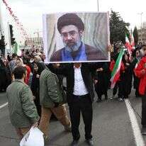 גבר איראני מחזיק תמונה של מוג'תבא חמינאי, בנו של המנהיג העליון של איראן, כשהוא משתתף בחגיגות 47 שנה למהפכה האסלאמית בטהרן | EPA