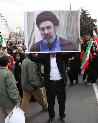 גבר איראני מחזיק תמונה של מוג'תבא חמינאי, בנו של המנהיג העליון של איראן, כשהוא משתתף בחגיגות 47 שנה למהפכה האסלאמית בטהרן | EPA
