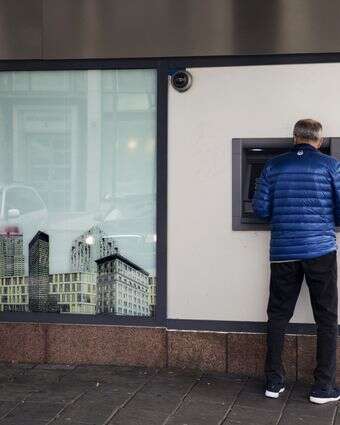 לקוח משתמש במכשיר כספומט מחוץ לסניף בנק | קירה ליין/בלומברג