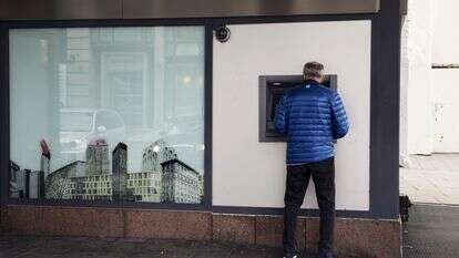 לקוח משתמש במכשיר כספומט מחוץ לסניף בנק | קירה ליין/בלומברג