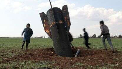 ילדים משחקים סביב טיל שלא התפוצץ שנחת בשדה פתוח בסוריה | דליל סולימאן / AFP