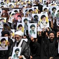 מפגינים בעיר קראצ'י מניפים השבוע את תמונותיהם של עלי ומוג'תבא חמינאי | AFP