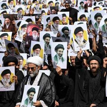 מפגינים בעיר קראצ'י מניפים השבוע את תמונותיהם של עלי ומוג'תבא חמינאי | AFP