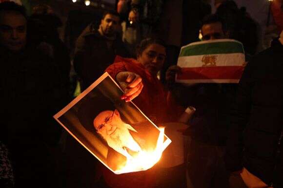 מפגינים הציתו דיוקן של המנהיג העליון של איראן, עלי חמינאי, בעת השתתפותם בעצרת תמיכה בתנועת המחאה הנוכחית באיראן | EPA/NEIL HALL מפגינים הציתו דיוקן של המנהיג העליון של איראן, עלי חמינאי, בעת השתתפותם בעצרת תמיכה בתנועת המחאה הנוכחית באיראן | EPA/NEIL HALL