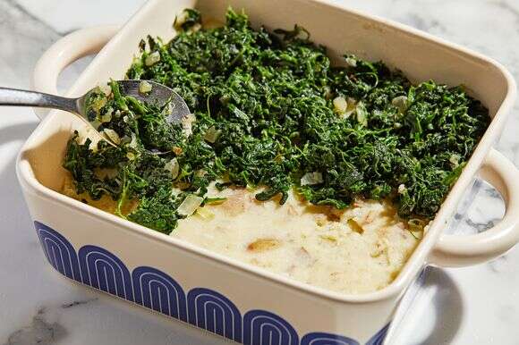 חצי מהפירה העשיר, המושרה בשום, מורחים בשכבות בתבנית קדירה, ומעליה מכוסה תרד קצוץ מוקפץ עם בצל, מלח ופלפל | טום מקורקל עבור הוושינגטון פוסט; עיצוב אוכל מאת ג'ינה ניסטיקו עבור הוושינגטון פוסט