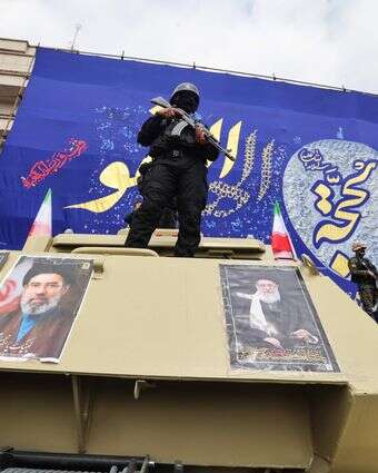 חיילי משמרות המהפכה עומדים על כלי רכב משוריינים עם תמונות המנהיג העליון שחוסל, עלי חמינאי, ובנו, שנבחר למחליפו | AFP