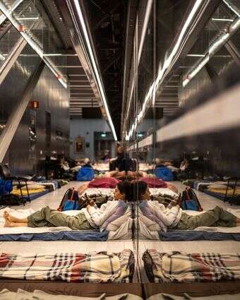 אישה משתמשת בטלפון נייד כשהיא שוכבת על מזרן בתחנת רכבת ששימשה כמקלט תת-קרקעי | אולימפיה דה מייסמונט / AFP