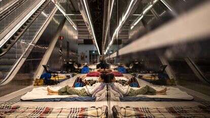 אישה משתמשת בטלפון נייד כשהיא שוכבת על מזרן בתחנת רכבת ששימשה כמקלט תת-קרקעי | אולימפיה דה מייסמונט / AFP