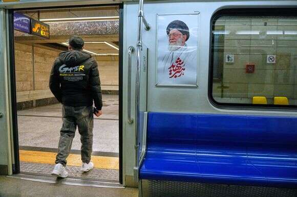 גבר יורד מרכבת תחתית ליד תמונה של המנהיג העליון האיראני המנוח, האייתוללה עלי חמינאי, בטהרן, איראן | AP Photo/Vahid Salemi גבר יורד מרכבת תחתית ליד תמונה של המנהיג העליון האיראני המנוח, האייתוללה עלי חמינאי, בטהרן, איראן | AP Photo/Vahid Salemi