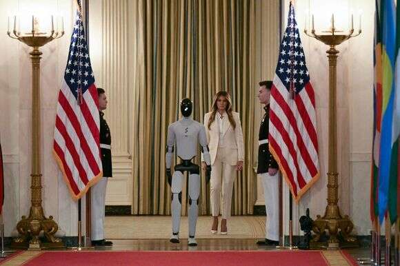 הגברת הראשונה של ארה"ב, מלניה טראמפ, הולכת עם רובוט דמוי אדם כשהיא מגיעה לפסגת הקואליציה העולמית "טיפוח העתיד יחד" בחדר המזרחי של הבית הלבן בוושינגטון הבירה | Oliver Contreras / AFP