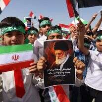 ילדים עיראקים תומכי המשטר האיראני מניפים תמונות של המנהיג העליון שחוסל עלי חמינאי ודגלי הרפובליקה האסלאמית | AFP