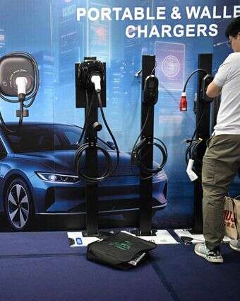 עובד מסדר סוגים שונים של מטענים לרכב חשמלי תוצרת סין, המוצגים ביום הפתיחה של תערוכת הרכב הבינלאומית במנילה | AFP