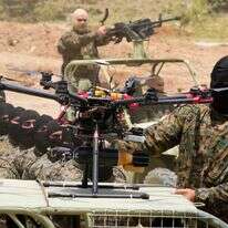 לוחם חיזבאללה עומד ליד רחפן חמוש במהלך תרגיל אימון בכפר ערמטה במחוז ג'זין, דרום לבנון, ב-21 במאי 2023 | AP