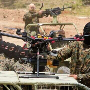 לוחם חיזבאללה עומד ליד רחפן חמוש במהלך תרגיל אימון בכפר ערמטה במחוז ג'זין, דרום לבנון, ב-21 במאי 2023 | AP