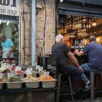אנשים יושבים בבית קפה ליד מוכר תבלינים בשוק מחנה יהודה בירושלים | נועם רבקין פנטון, פלאש 90