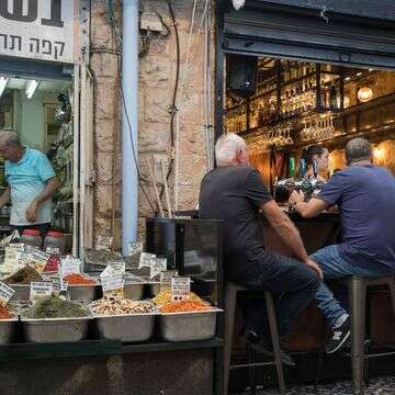 אנשים יושבים בבית קפה ליד מוכר תבלינים בשוק מחנה יהודה בירושלים | נועם רבקין פנטון, פלאש 90