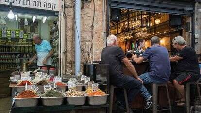 אנשים יושבים בבית קפה ליד מוכר תבלינים בשוק מחנה יהודה בירושלים | נועם רבקין פנטון, פלאש 90