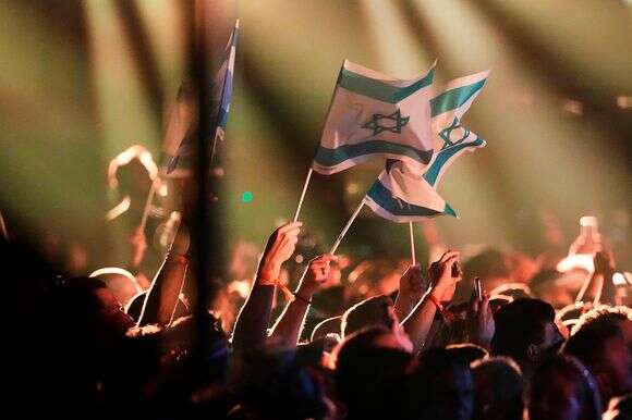 דגלי ישראל מנופפים על ידי הקהל בזמן שנועם בתן מישראל מבצע את השיר "מישל" בחצי הגמר הראשון של תחרות האירוויזיון ה-70 בווינה | AP/מרטין מייזנר