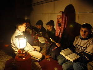 אין חשמל. אימאם קורא מהקוראן בפני הילדים במחנה ג'בליה באמצעות עששית אין חשמל. אימאם קורא מהקוראן בפני הילדים במחנה ג'בליה באמצעות עששית