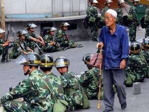 תושב מוסלמי צועד ליד חיילים באורומצ'י. תושב מוסלמי צועד ליד חיילים באורומצ'י.