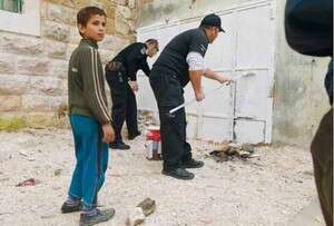 תושב חברון ושוטר ישראלי צובעים כניסה לחנות תושב חברון ושוטר ישראלי צובעים כניסה לחנות