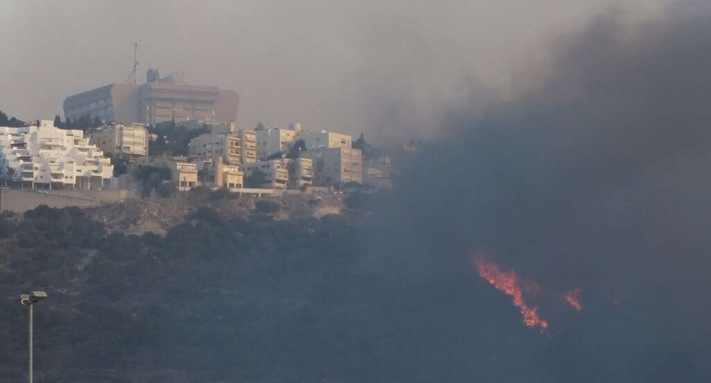 בצילום - ביה"ח כרמל מוקף באש, מגינים על מיכלי החמצן של ביה"ח קרדיט - צילום אלי דדון