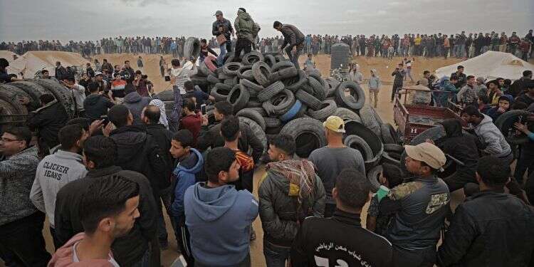 פלסטינים אוספים צמיגים בגבול עזה. צילום: EPA צילום: EPA