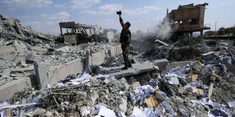 חייל סורי בודק את הריסות מבנה המתואר כחלק ממתחם המדעים והמדע (SSRC) במחוז ברזה, צפונית לדמשק. צילום: AP צילום: AP