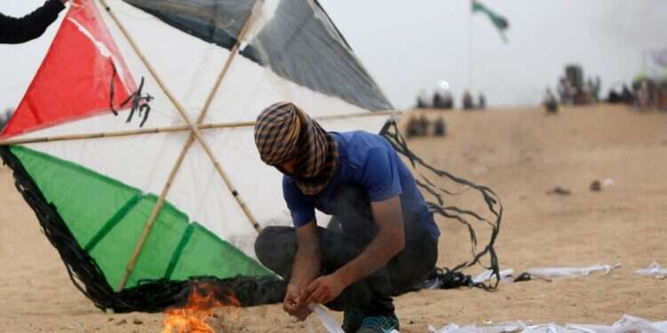 פלסטיני מצית עפיפון ברצועת עזה. צילום: AFP פלסטיני מצית עפיפון ברצועת עזה. צילום: AFP